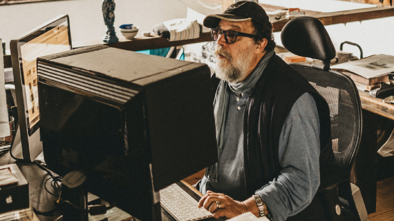 Imagem mostra um senhor de mais idade usando um computador com 20 anos de fabricação